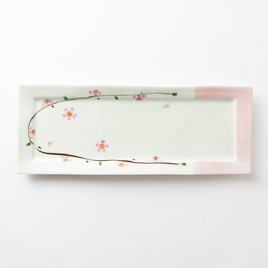 Rectangular serving plate viewed from above, featuring a delicate cherry blossom pattern along one edge with soft pink accents on the corners.