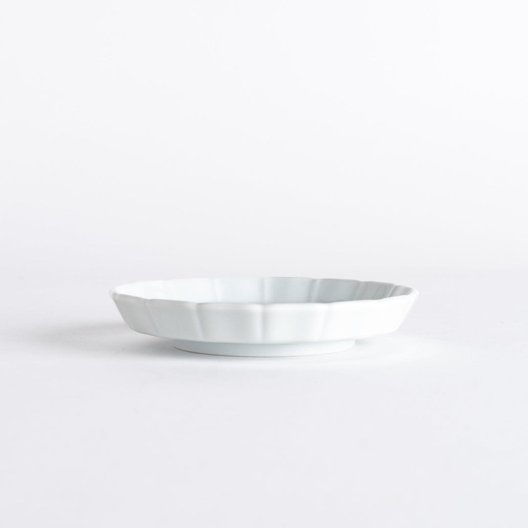 A small round plate with a traditional Japanese design depicting a landscape and floral elements.
