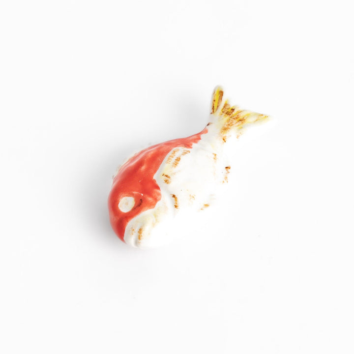 Chopstick rest shaped like a sea bream, intricately painted with red and white hues.