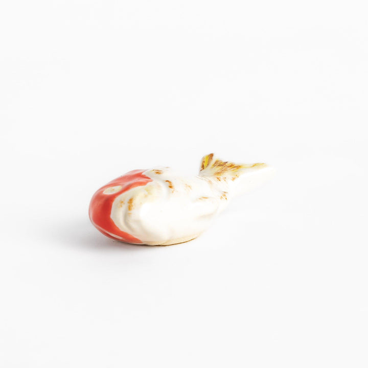 Chopstick rest shaped like a sea bream, intricately painted with red and white hues.