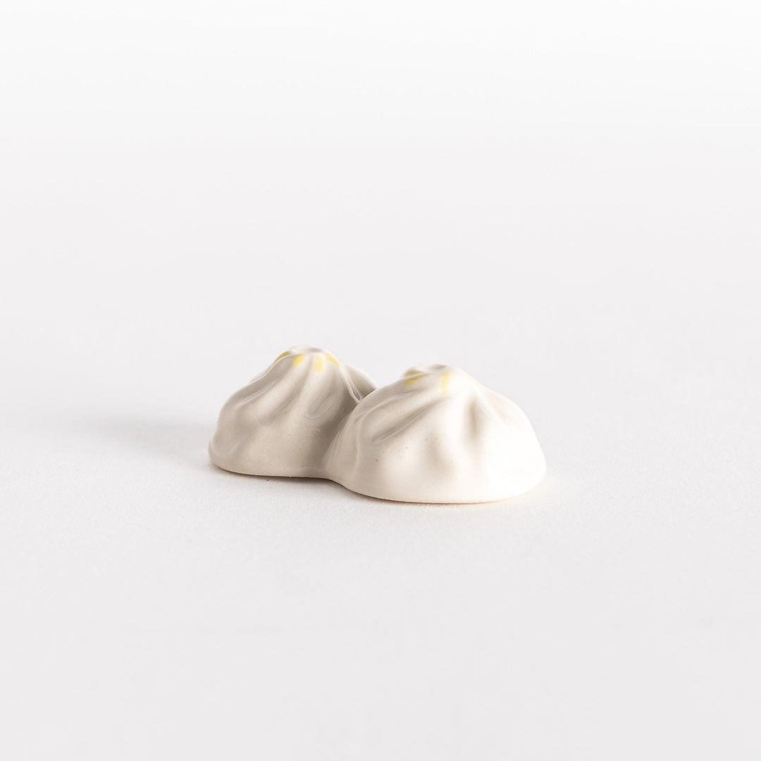 Angled view of a soup dumpling-shaped chopstick rest, highlighting its delicate folds and smooth finish.