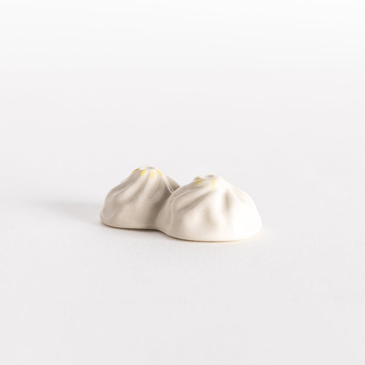 Angled view of a soup dumpling-shaped chopstick rest, highlighting its delicate folds and smooth finish.