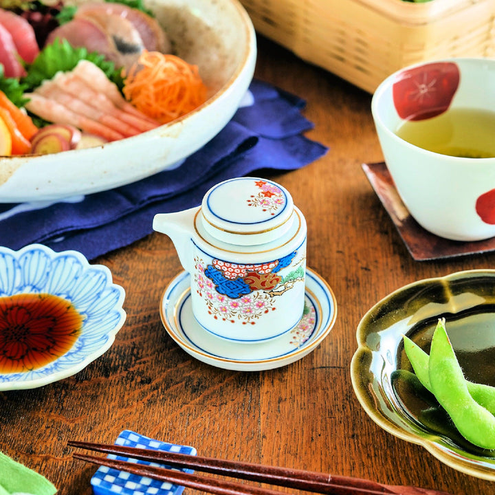 Soy sauce dispenser with a traditional Spring and Autumn motif, featuring floral and fan patterns in red and blue, placed on a matching saucer.