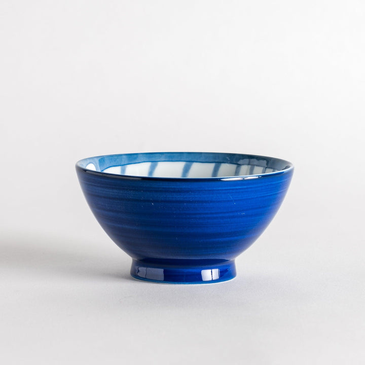 A rice bowl with a blue-striped white cat, curled up and smiling.