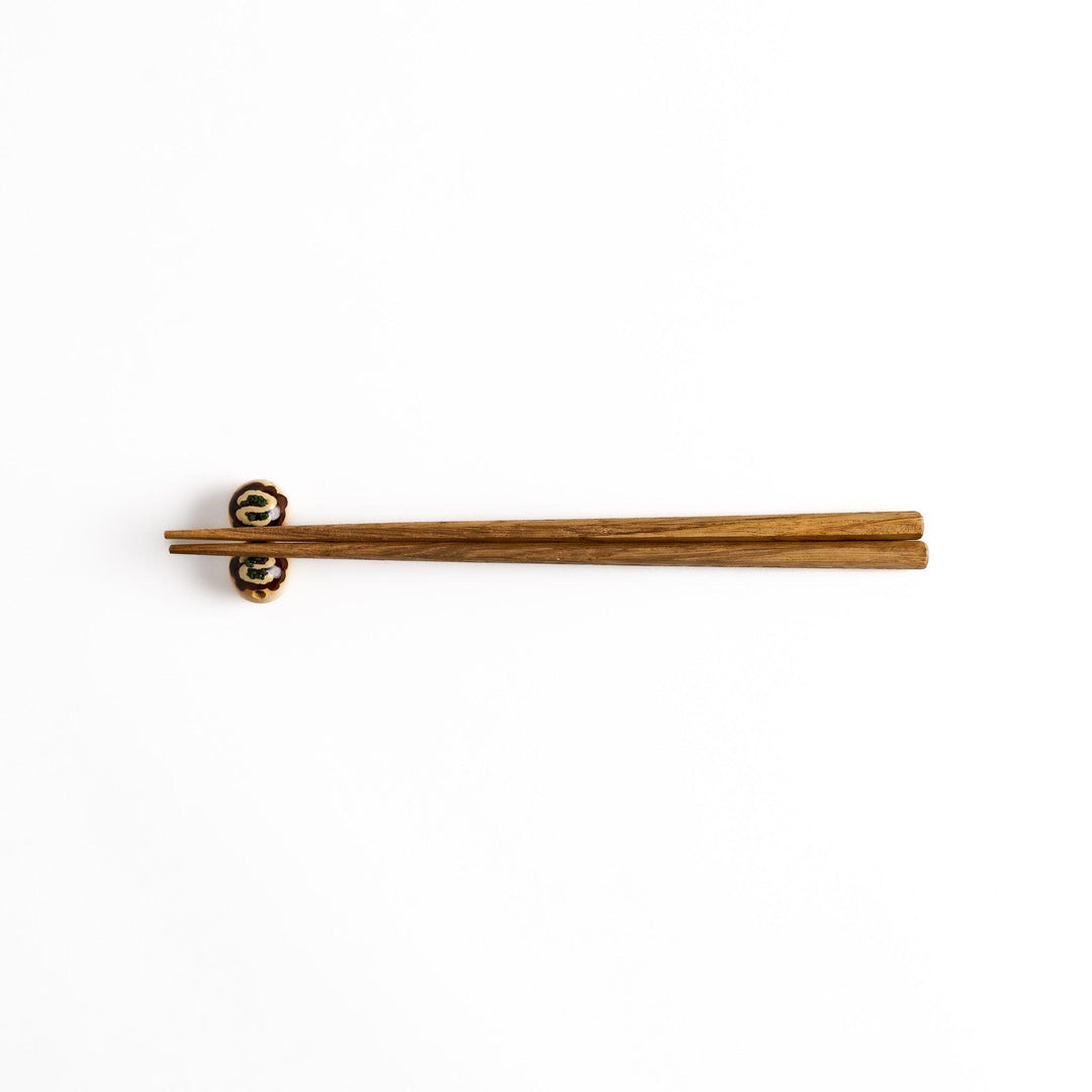 Wooden chopsticks resting on a pair of takoyaki-shaped chopstick rests, a fun and functional addition to any Japanese dining setting.