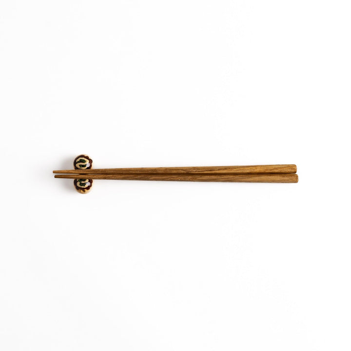 Wooden chopsticks resting on a pair of takoyaki-shaped chopstick rests, a fun and functional addition to any Japanese dining setting.
