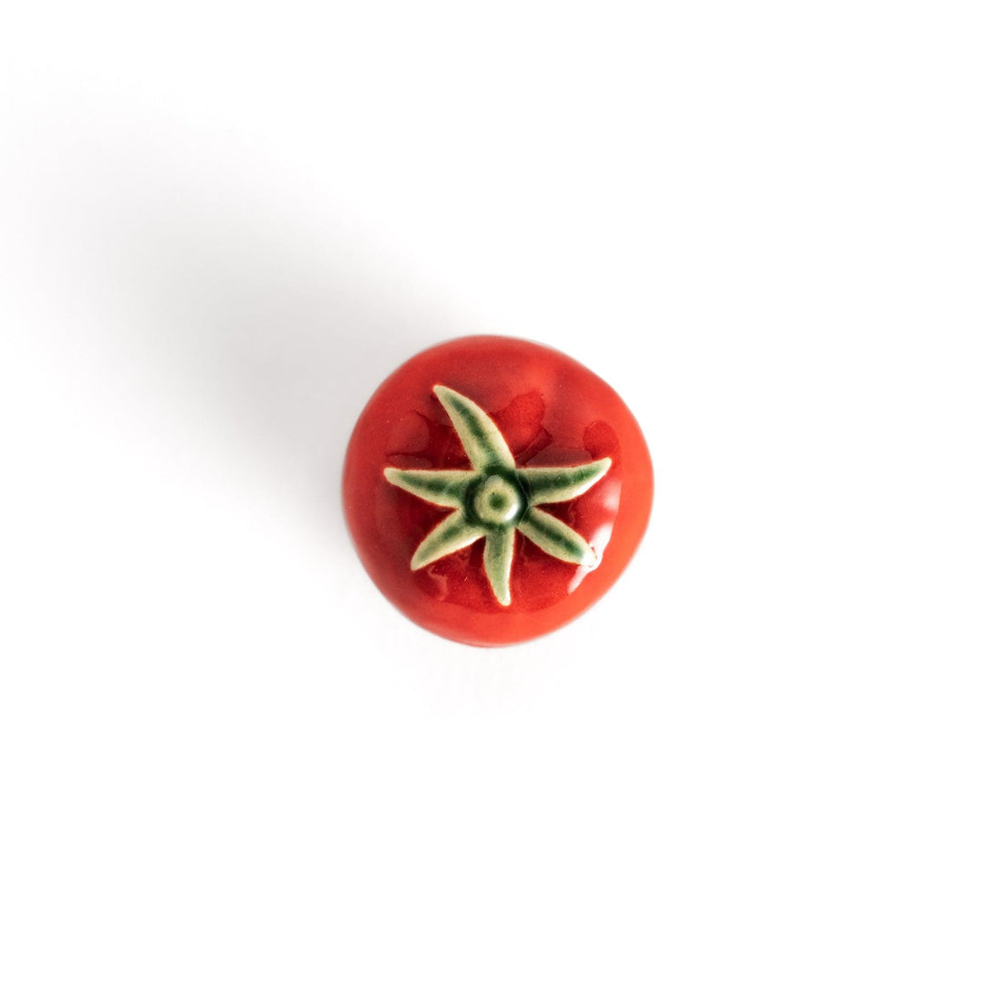 Glossy red ceramic tomato chopstick rest with a green stem detail, adding a playful yet elegant touch to your tableware setting.