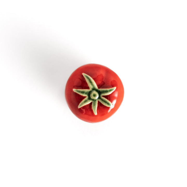 Glossy red ceramic tomato chopstick rest with a green stem detail, adding a playful yet elegant touch to your tableware setting.