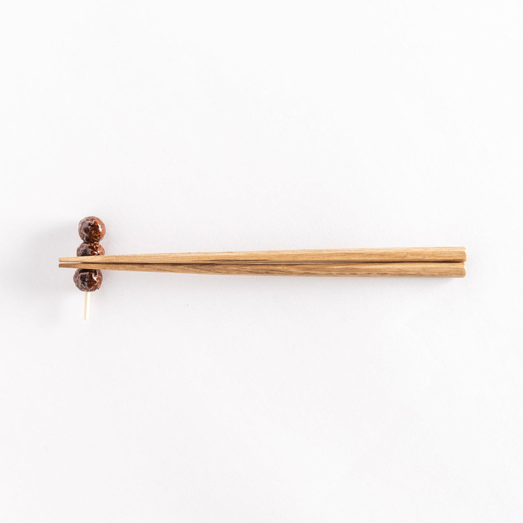 Chopsticks placed on the skewer-shaped chopsticks rest, highlighting the meatball details.