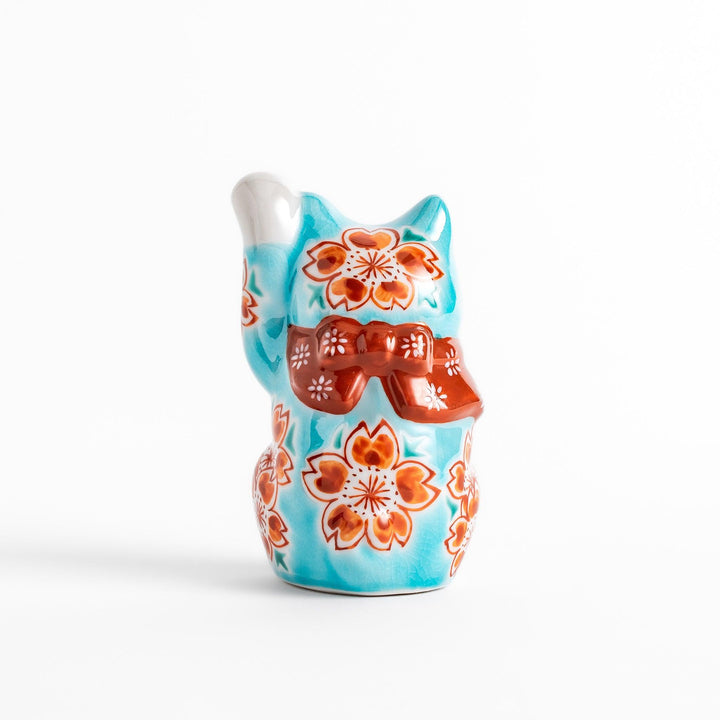 Vibrant Turkish blue Maneki Neko figurine adorned with floral patterns in orange and white, featuring a golden bell and a raised paw, symbolizing good fortune and prosperity.