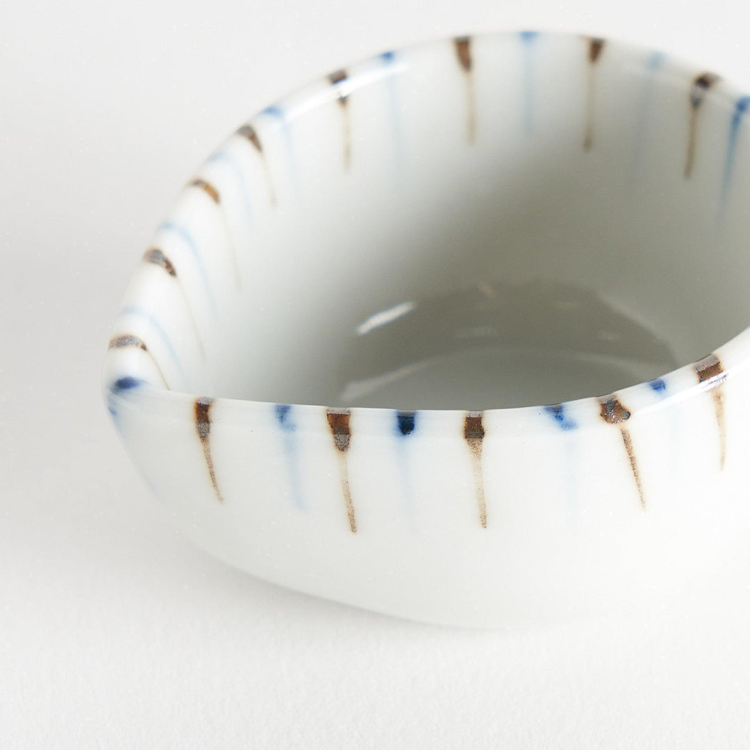 A small, curved condiment bowl featuring vertical blue and brown stripes.