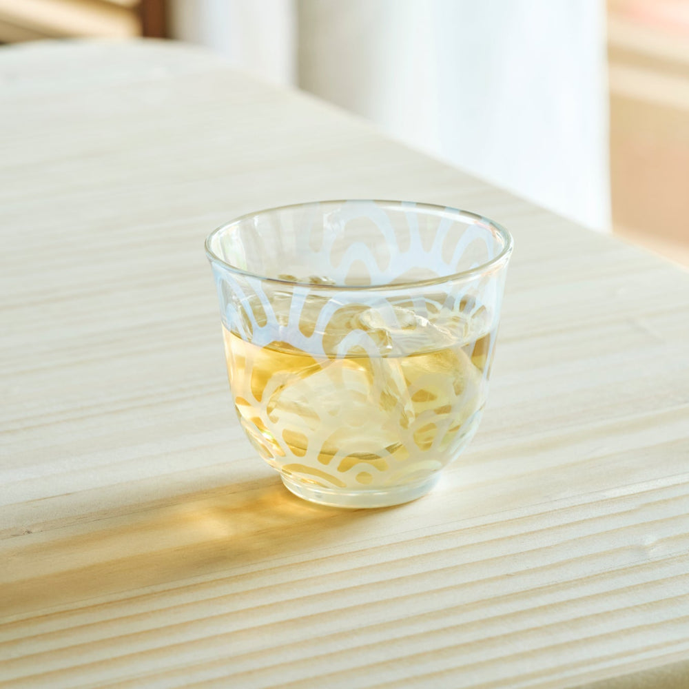 Vintage wave glass cup filled with iced tea on a wooden table for a refreshing and authentic Japanese tea time