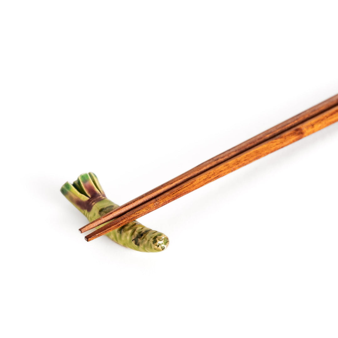 Wooden chopsticks delicately balanced on the ceramic wasabi chopstick rest, highlighting its realistic design and functional elegance.