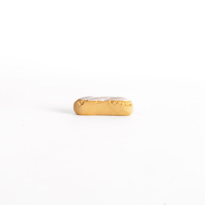 Side view of the white chocolate éclair-shaped chopsticks rest, capturing its elongated shape and delicate white chocolate detailing.