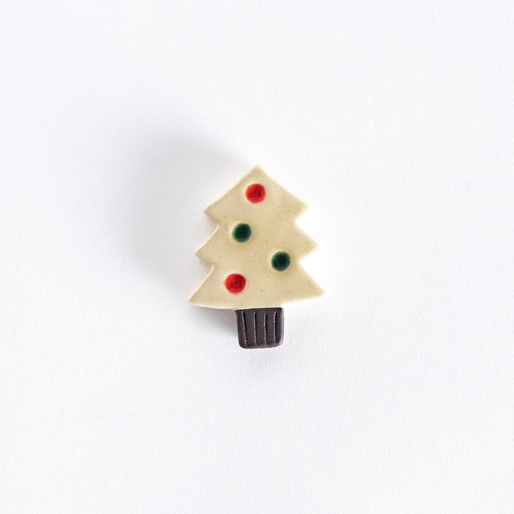 A ceramic chopsticks rest shaped like a white Christmas tree with red and green ornaments.