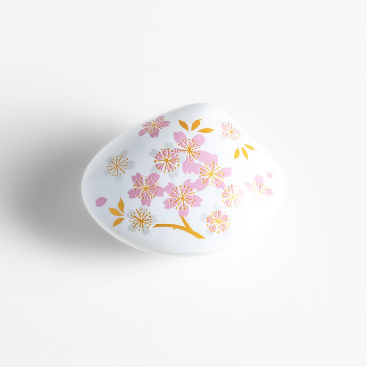 White ceramic incense holder shaped like a seashell, adorned with delicate pink and gold cherry blossoms, featuring a sakura-shaped holder for a refined touch.