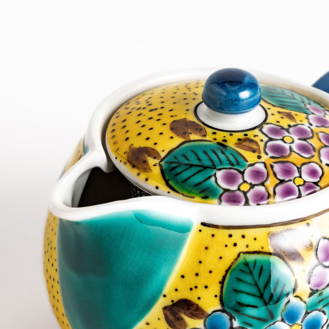 Vibrant yellow ceramic teapot with a colorful hydrangea pattern and a contrasting green spout. Perfect for adding a touch of cheer to your tea time.